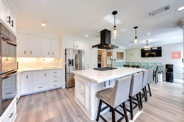 1950 Country Club Rd, Brenham, TX 77833 - kitchen featuring appliances with stainless steel finishes, island range hood, decorative backsplash, light stone counters, and a center island