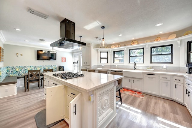 1950 Country Club Rd, Brenham, TX 77833 - kitchen with stainless steel gas stovetop, island range hood, healthy amount of natural light, a center island, and ornamental molding