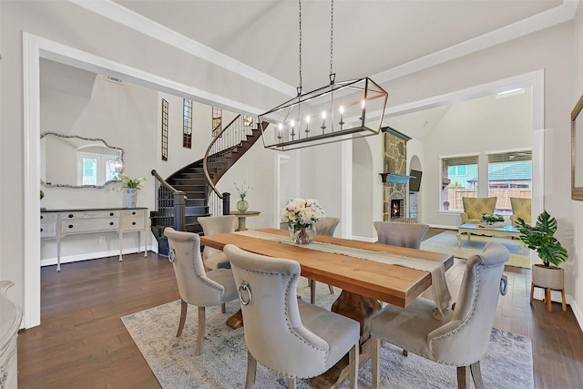 1107 Rymers Switch Ln, Friendswood, TX 77546 - dining area featuring dark wood-style floors, stairway, a chandelier, ornamental molding, and a stone fireplace