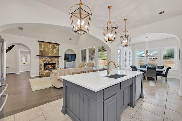 1107 Rymers Switch Ln, Friendswood, TX 77546 - kitchen featuring gray cabinetry, a chandelier, light countertops, a fireplace, and a center island with sink