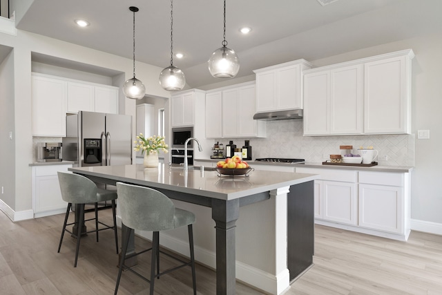 910 Hooks Trl, League City, TX 77573 - kitchen featuring stainless steel appliances, under cabinet range hood, backsplash, a kitchen breakfast bar, and a center island with sink