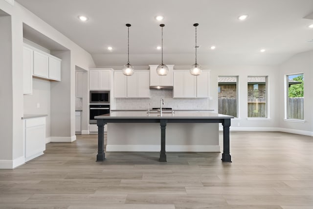 910 Hooks Trl, League City, TX 77573 - kitchen with black oven, stainless steel microwave, white cabinets, lofted ceiling, and decorative backsplash