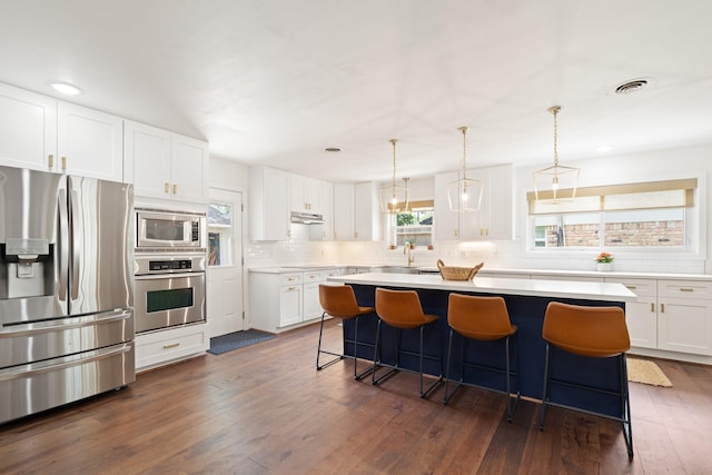 3006 Ann Arbor Dr, Houston, TX 77063 - kitchen with stainless steel appliances, decorative backsplash, a kitchen breakfast bar, white cabinetry, and under cabinet range hood