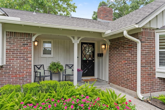 3006 Ann Arbor Dr, Houston, TX 77063 - view of exterior entry with a chimney, brick siding, roof with shingles, board and batten siding, and covered porch