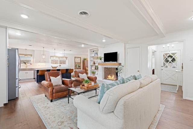3006 Ann Arbor Dr, Houston, TX 77063 - living room featuring beam ceiling, hardwood / wood-style floors, a warm lit fireplace, and crown molding