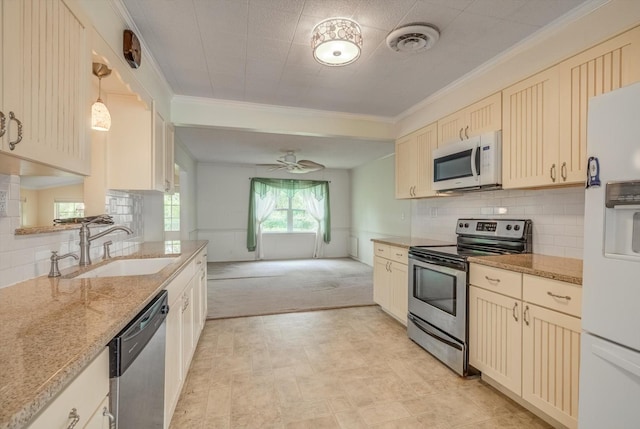 211 Magnolia St, Lake Jackson, TX 77566 - kitchen with appliances with stainless steel finishes, ornamental molding, cream cabinets, ceiling fan, and light stone countertops