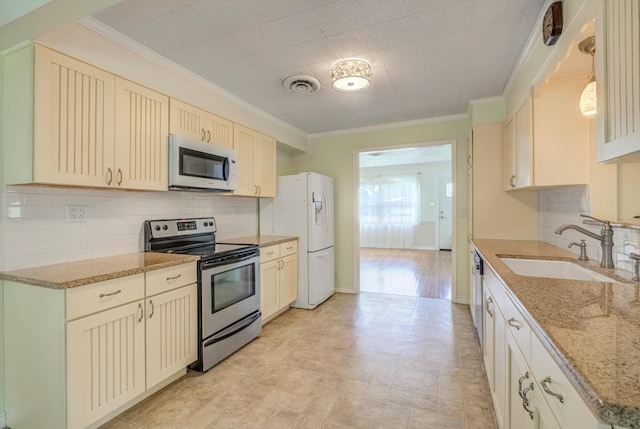 211 Magnolia St, Lake Jackson, TX 77566 - kitchen featuring appliances with stainless steel finishes, crown molding, decorative backsplash, light stone countertops, and cream cabinets