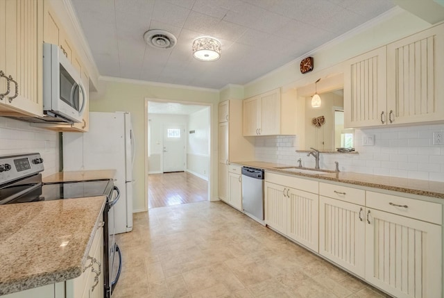211 Magnolia St, Lake Jackson, TX 77566 - kitchen with stainless steel appliances, crown molding, cream cabinetry, decorative backsplash, and light stone counters