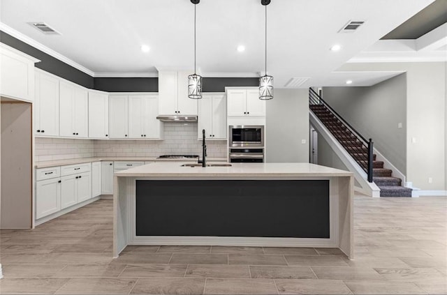 427 Rd 66111, Dayton, TX 77535 - kitchen with crown molding, appliances with stainless steel finishes, decorative backsplash, light countertops, and a center island with sink