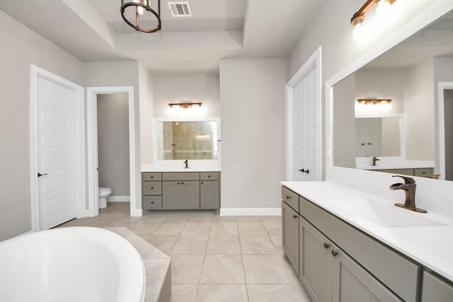 1831 Golden Cape Dr, Katy, TX 77494 - bathroom featuring two vanities, a raised ceiling, a bathtub, and tile patterned floors