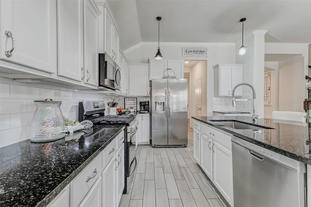 28638 Monarch Cliffs Dr, Fulshear, TX 77441 - kitchen with stainless steel appliances, white cabinetry, ornamental molding, hanging light fixtures, and dark stone counters