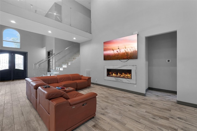 5215 Kelso St, Houston, TX 77021 - living area with a high ceiling, stairs, a lit fireplace, light wood-style flooring, and french doors