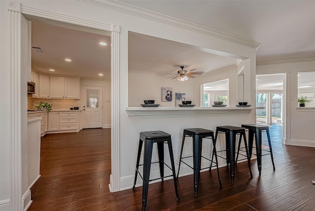 1714 Maux Dr, Houston, TX 77043 - kitchen with black microwave, crown molding, a kitchen bar, light countertops, and dark wood-style flooring