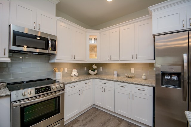 803 Cherokee Dr, Conroe, TX 77316 - kitchen with stainless steel appliances, white cabinetry, wood finished floors, backsplash, and glass insert cabinets