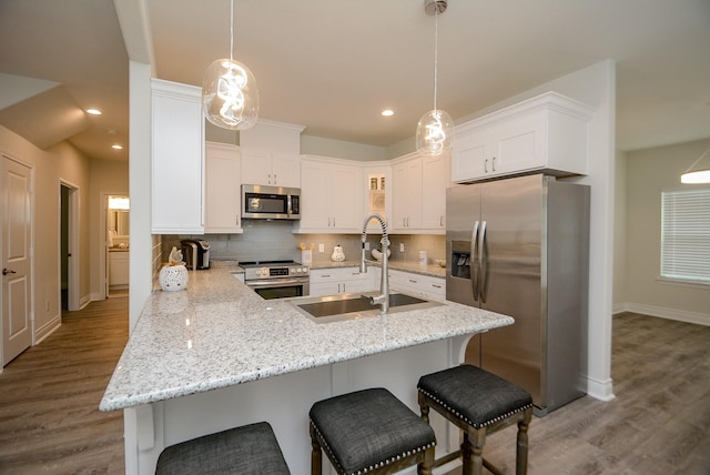 803 Cherokee Dr, Conroe, TX 77316 - kitchen featuring appliances with stainless steel finishes, a peninsula, white cabinets, dark wood finished floors, and recessed lighting