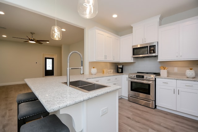 803 Cherokee Dr, Conroe, TX 77316 - kitchen with appliances with stainless steel finishes, recessed lighting, decorative backsplash, light wood finished floors, and a peninsula