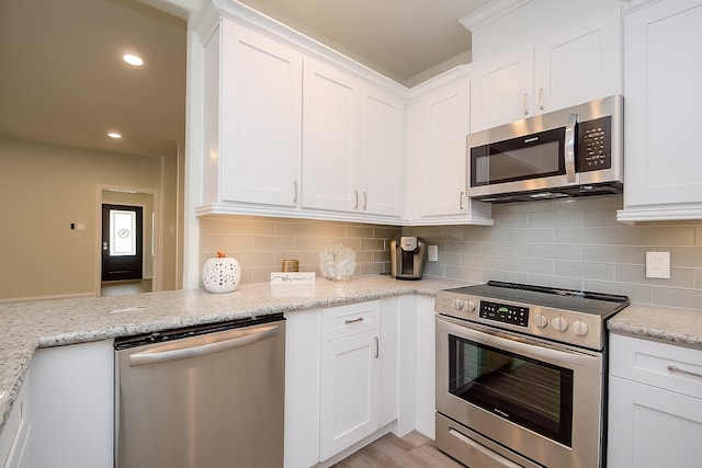 803 Cherokee Dr, Conroe, TX 77316 - kitchen with appliances with stainless steel finishes, white cabinets, decorative backsplash, light stone counters, and recessed lighting