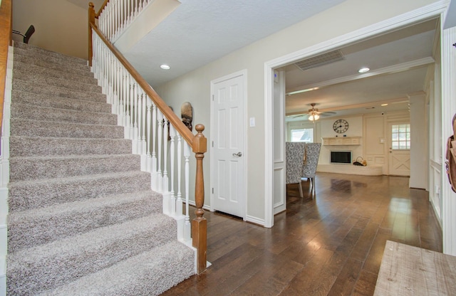 6711 Pebble Beach Dr, Houston, TX 77069 - staircase featuring wood-type flooring, a fireplace with raised hearth, a ceiling fan, healthy amount of natural light, and ornamental molding