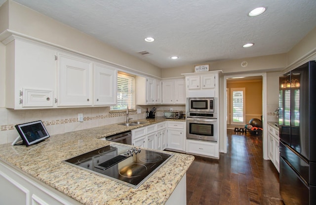 6711 Pebble Beach Dr, Houston, TX 77069 - kitchen featuring appliances with stainless steel finishes, dark wood-type flooring, a peninsula, white cabinetry, and recessed lighting