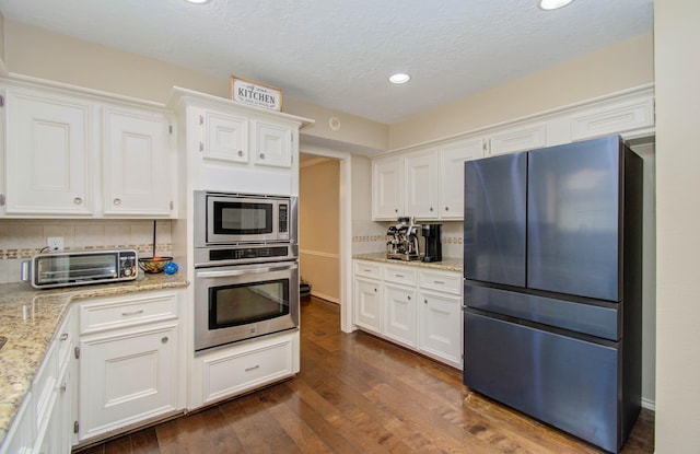 6711 Pebble Beach Dr, Houston, TX 77069 - kitchen featuring appliances with stainless steel finishes, white cabinetry, recessed lighting, dark wood-type flooring, and light stone countertops