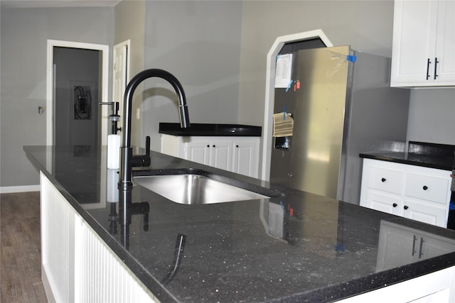 25 Wood Gln, Trinity, TX 75862 - kitchen with freestanding refrigerator, dark wood-type flooring, white cabinetry, and dark stone countertops