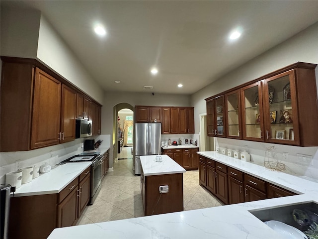 17907 Camp Cove Dr, Cypress, TX 77429 - kitchen with appliances with stainless steel finishes, arched walkways, light stone countertops, recessed lighting, and light tile patterned floors