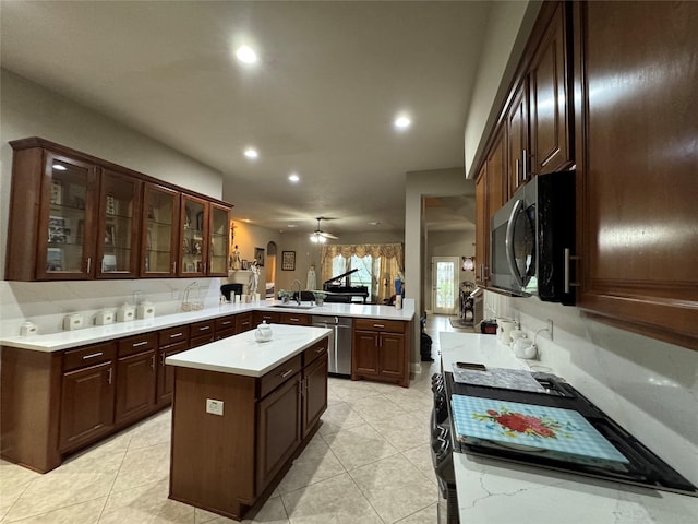 17907 Camp Cove Dr, Cypress, TX 77429 - kitchen with appliances with stainless steel finishes, a peninsula, light countertops, recessed lighting, and glass insert cabinets