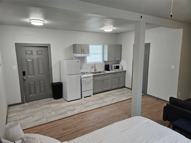 208 W 2nd St, Sweeny, TX 77480 - kitchen featuring white appliances, gray cabinetry, under cabinet range hood, wood tiled floors, and light countertops