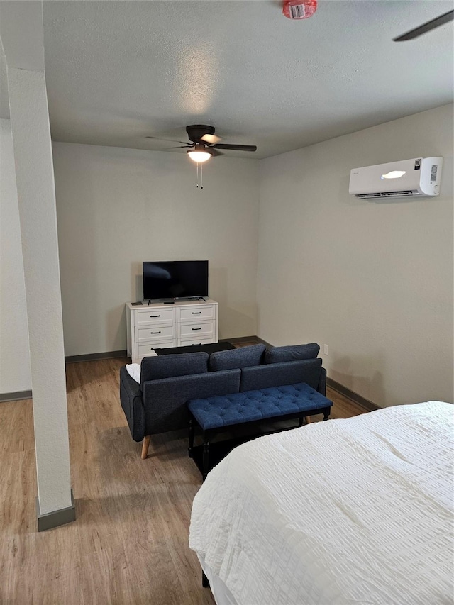 208 W 2nd St, Sweeny, TX 77480 - bedroom with a wall mounted air conditioner, wood finished floors, ceiling fan, and a textured ceiling