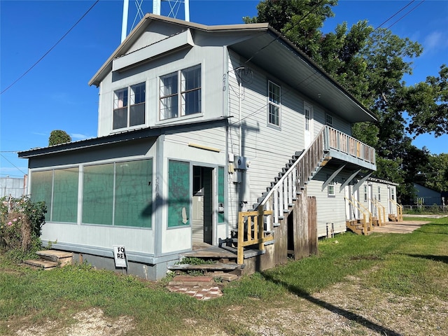 208 W 2nd St, Sweeny, TX 77480 - view of home's exterior featuring entry steps, a sunroom, a lawn, and stairs