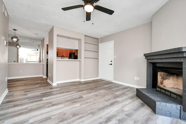 1505 Ward Rd Unit 182, Baytown, TX 77520 - unfurnished living room featuring wood finished floors, a textured ceiling, ceiling fan, a fireplace, and built in shelves