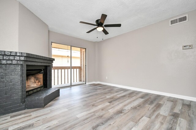 1505 Ward Rd Unit 182, Baytown, TX 77520 - unfurnished living room featuring a fireplace, wood finished floors, a ceiling fan, and a textured ceiling