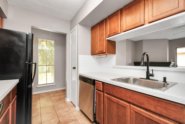 1505 Ward Rd Unit 182, Baytown, TX 77520 - kitchen with freestanding refrigerator, stainless steel dishwasher, light countertops, light tile patterned flooring, and brown cabinetry