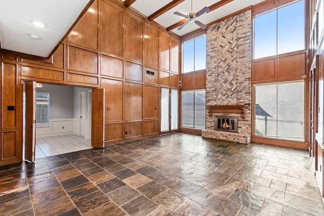 3318 Teawick Ct, Houston, TX 77068 - unfurnished living room with a decorative wall, a towering ceiling, a ceiling fan, stone tile flooring, and a brick fireplace