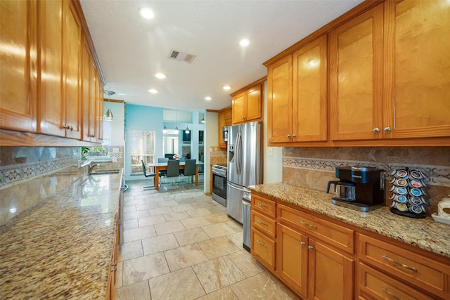 17383 Harbor Dr, Montgomery, TX 77356 - kitchen featuring brown cabinetry, appliances with stainless steel finishes, decorative backsplash, light stone counters, and recessed lighting