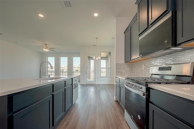 2040 Terra Rose Dr, Katy, TX 77493 - kitchen with stainless steel gas stove, backsplash, light countertops, wood finished floors, and recessed lighting