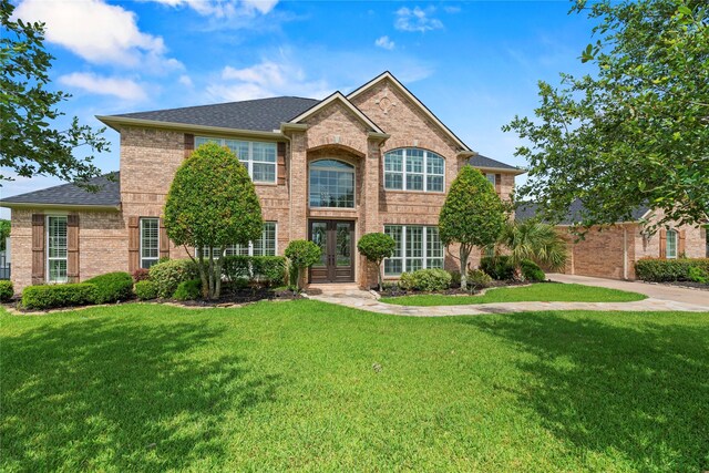 3211 Lakes Of Katy Ln, Katy, TX 77493 - traditional-style house with french doors, brick siding, a front yard, and a shingled roof