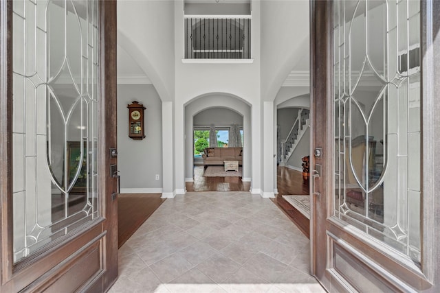3211 Lakes Of Katy Ln, Katy, TX 77493 - entryway with arched walkways, a high ceiling, stairway, light tile patterned floors, and ornamental molding