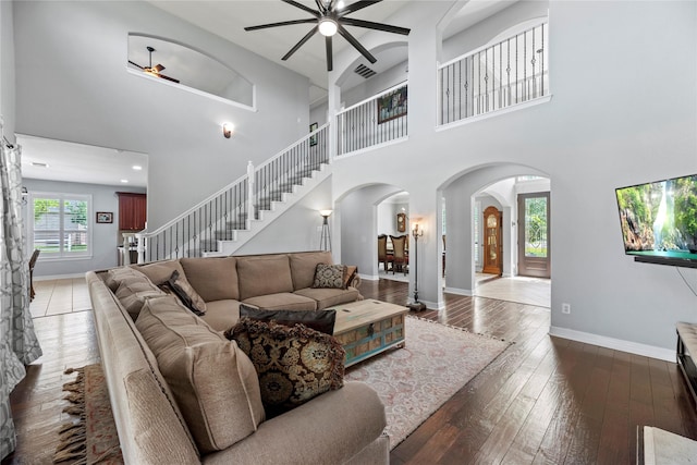 3211 Lakes Of Katy Ln, Katy, TX 77493 - living area featuring arched walkways, ceiling fan, wood-type flooring, a towering ceiling, and stairs
