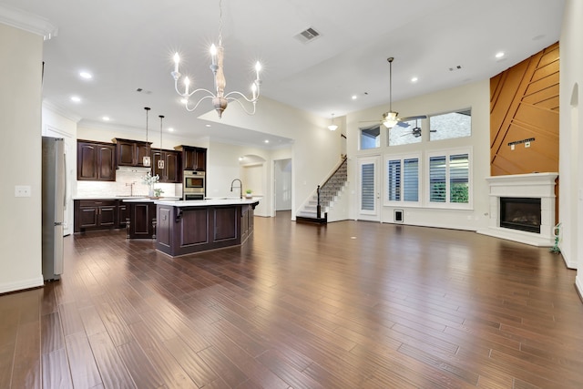 15 Floral Hills Ln, Fulshear, TX 77441 - kitchen featuring appliances with stainless steel finishes, open floor plan, light countertops, dark brown cabinetry, and an island with sink