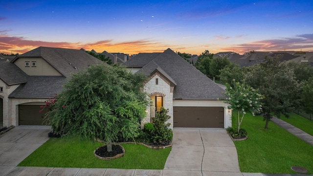15 Floral Hills Ln, Fulshear, TX 77441 - french country style house featuring a shingled roof, concrete driveway, and stone siding