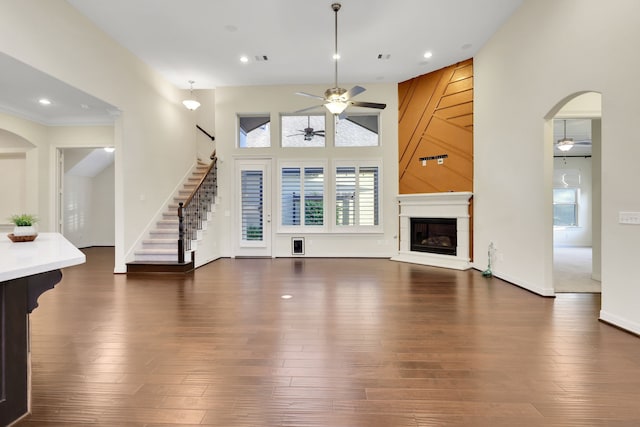 15 Floral Hills Ln, Fulshear, TX 77441 - unfurnished living room featuring ceiling fan, stairs, arched walkways, a glass covered fireplace, and recessed lighting