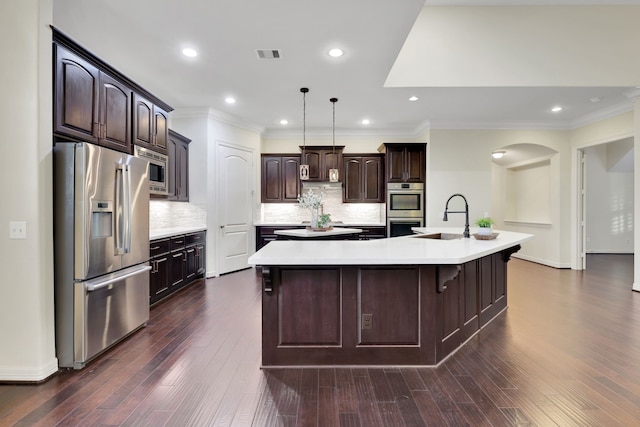 15 Floral Hills Ln, Fulshear, TX 77441 - kitchen featuring appliances with stainless steel finishes, a large island with sink, dark brown cabinetry, light countertops, and crown molding