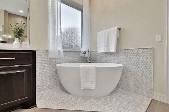 15 Floral Hills Ln, Fulshear, TX 77441 - bathroom with tile patterned flooring, a soaking tub, vanity, tile walls, and a wainscoted wall