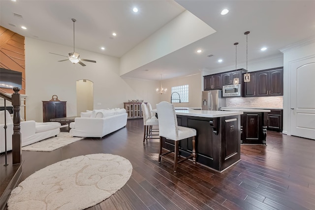 15 Floral Hills Ln, Fulshear, TX 77441 - kitchen with stainless steel appliances, a center island with sink, light countertops, a kitchen breakfast bar, and dark brown cabinetry