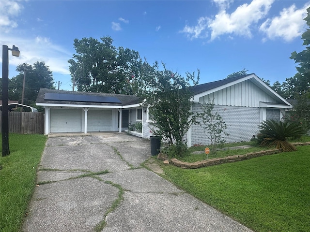 4522 Sage Cir, Baytown, TX 77521 - ranch-style home featuring solar panels, brick siding, concrete driveway, an attached garage, and board and batten siding