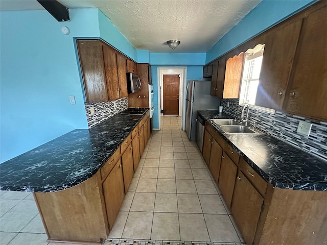 4522 Sage Cir, Baytown, TX 77521 - kitchen with stainless steel appliances, tasteful backsplash, light tile patterned flooring, a peninsula, and a textured ceiling