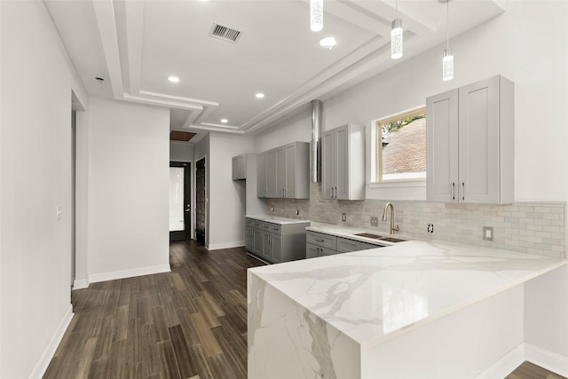4817 Los Angeles St, Houston, TX 77026 - kitchen with gray cabinets, light stone counters, backsplash, a peninsula, and dark wood-style floors