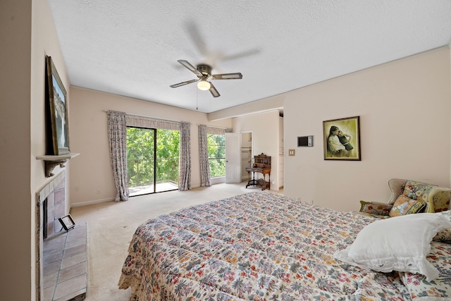 9 Farther Pt, Houston, TX 77024 - bedroom with carpet floors, a tiled fireplace, ceiling fan, access to exterior, and a textured ceiling