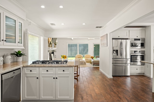 12422 Cobblestone Dr, Houston, TX 77024 - kitchen with appliances with stainless steel finishes, a peninsula, white cabinets, ornamental molding, and glass insert cabinets